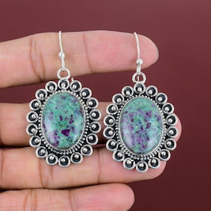 May include: A pair of silver earrings with green and purple gemstone oval cabochons set in a decorative silver frame.