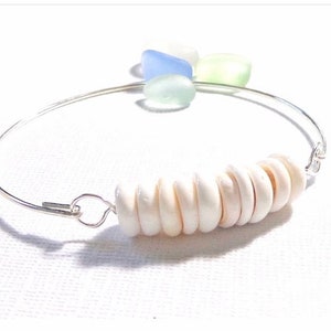 May include: A silver bangle bracelet with a row of white shell beads and blue and green sea glass accents.