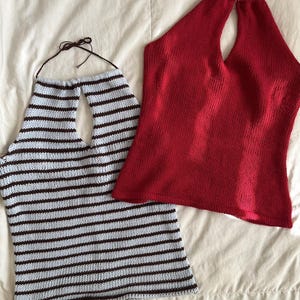 May include: Two knitted halter tops. One is light blue with horizontal brown stripes. The other is solid red. Both tops have a keyhole neckline and are made of a soft, textured material. The tops are displayed on a white surface.
