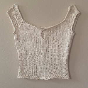 May include: A white crocheted off-the-shoulder top with short sleeves and a small keyhole opening in the back.