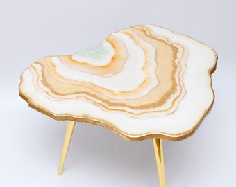 May include: A white and gold resin coffee table with a unique, organic shape and gold metal legs.