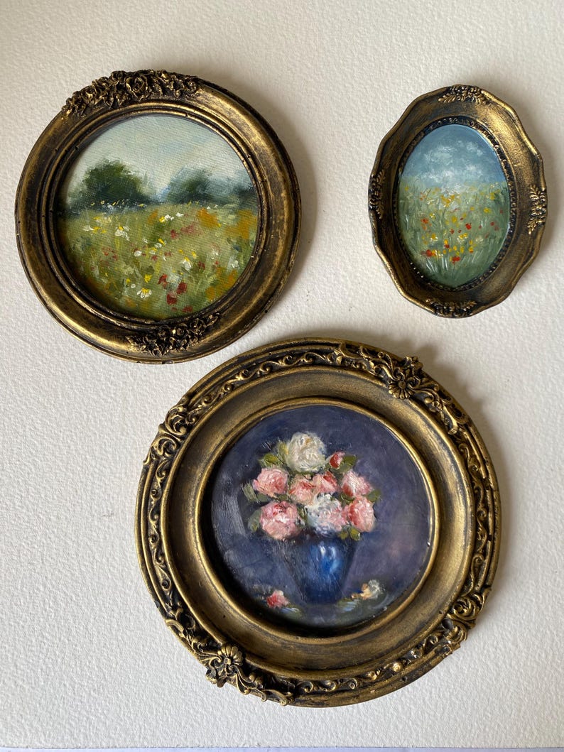May include: Three framed paintings with gold ornate frames. The paintings depict a field of wildflowers, a field of wildflowers with a blue sky, and a bouquet of pink roses in a blue vase.