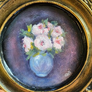 May include: A framed painting of a bouquet of pink flowers in a blue vase. The flowers are painted in a realistic style and the background is a dark purple.
