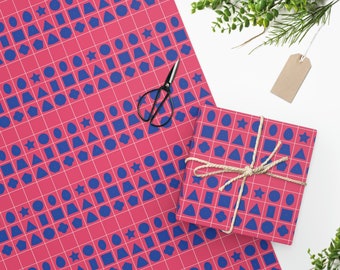 May include: A roll of pink wrapping paper and a wrapped gift box with a geometric pattern of blue shapes. The pattern includes squares, circles, stars, and other shapes on a grid. A pair of black scissors and a gift tag are also present.