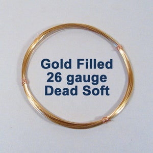 May include: A coil of gold-filled wire, 26 gauge, labeled "Dead Soft". The wire is a warm gold color, wound into a circular shape. The ends are secured with small copper-colored wraps.