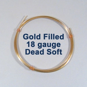 May include: A coil of gold-filled wire, 18 gauge, and dead soft. The wire is a bright gold color, and the text "Gold Filled 18 gauge Dead Soft" is printed in dark blue. The wire is wound into a circular shape.