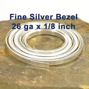 May include: A roll of 26 gauge fine silver bezel wire, 1/8 inch wide. The wire is coiled and appears to be shiny and smooth.