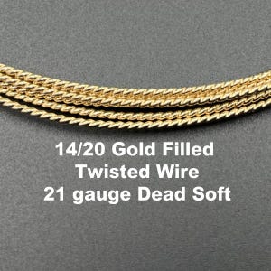 May include: Close-up of gold-filled twisted wire. The image shows several strands of 14/20 gold-filled wire, twisted and coiled. The text in the image reads "14/20 Gold Filled Twisted Wire 21 gauge Dead Soft."
