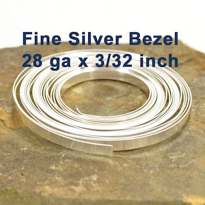 May include: A coil of fine silver bezel wire, 28 gauge and 3/32 inch wide. The wire is silver in color and has a smooth, polished finish.