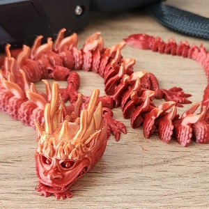 May include: A red and orange 3D printed dragon figurine with a detailed head and a segmented body.