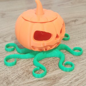 May include: A 3D printed orange pumpkin with a carved face and a green octopus base.