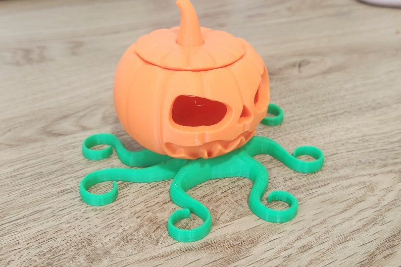 May include: A 3D printed orange pumpkin with a carved face and a green octopus base.