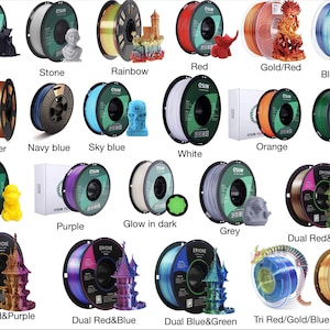Op de afbeelding: Assortiment van 16 spoelen filament voor 3D-printen in verschillende kleuren, waaronder zwart, wit, rood, blauw, groen, geel, paars, oranje, koper, goud en regenboog. Sommige spoelen hebben tweekleurige filamenten, zoals rood en groen, goud en paars, en rood en blauw. E&eacute;n spoel is gemarkeerd met "Glow in the dark".