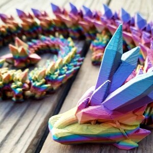 May include: A rainbow-colored, 3D printed dragon sculpture with a crystal-like texture. The dragon is curled up in a coil shape, with its head raised and its eyes closed.