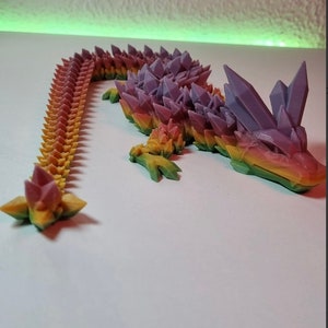 May include: A 3D printed rainbow colored lizard with a spiky, crystal-like texture. The lizard is posed with its tail curled up and its head raised.