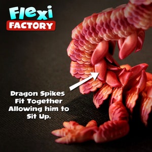 May include: A red and orange dragon figurine with a textured, scaly body. The dragon's spikes fit together, allowing it to sit up. The figurine is made by Flexi Factory.