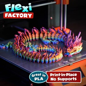 May include: A 3D printed dragon model in a rainbow iridescent color. The dragon is curled up on a black print bed. The text "Flexi FACTORY" is visible in the background. The text "Great in PLA" and "Print-in-Place No Supports" is visible in the foreground.