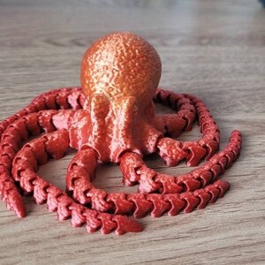 May include: A red octopus figurine with a textured surface and segmented tentacles.
