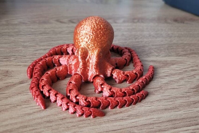 May include: A red octopus figurine with a textured surface and segmented tentacles.