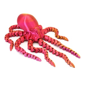May include: A pink and gold articulated octopus figurine with segmented tentacles. The octopus is made of plastic and has a shiny finish.