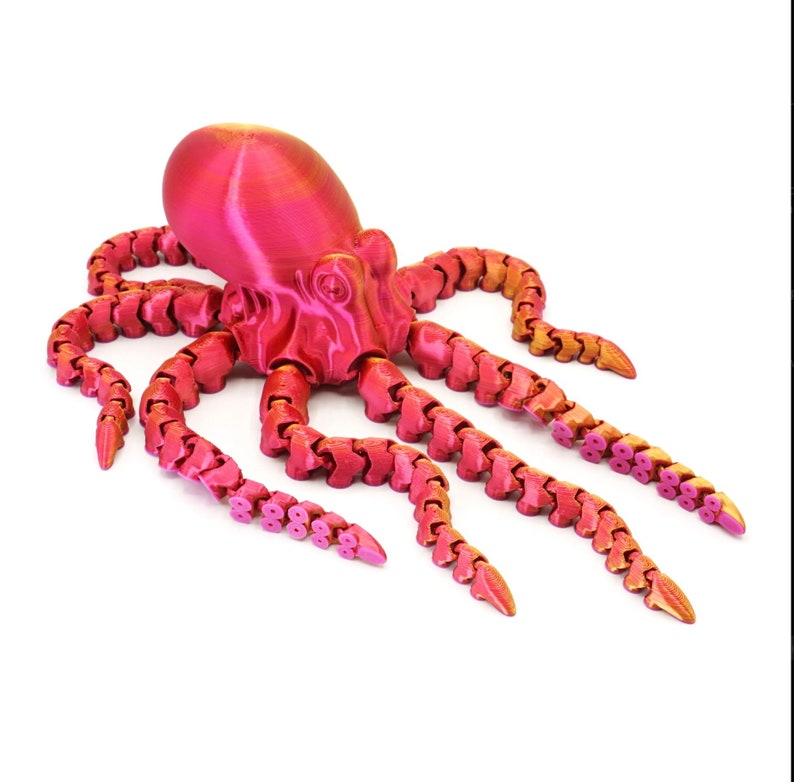 May include: A pink and gold articulated octopus figurine with segmented tentacles. The octopus is made of plastic and has a shiny finish.