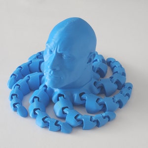 May include: A 3D printed blue sculpture of a person's head with a blue octopus-like body made of linked segments.