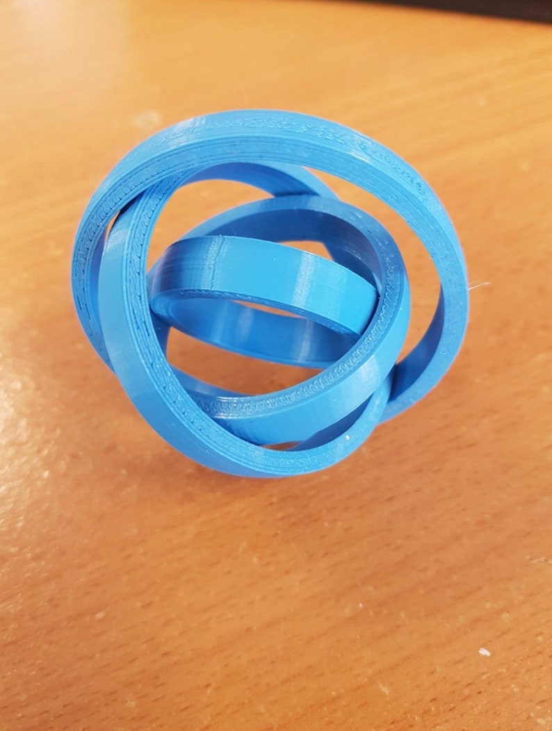 Puede incluir: Un objeto azul impreso en 3D que se asemeja a un nudo o una mara&ntilde;a de anillos.