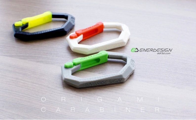 May include: Three 3D printed origami carabiners in black, white, and gray with green, red, and yellow accents. The carabiners are labeled "ENERDESIGN" and "ddf3d.com".