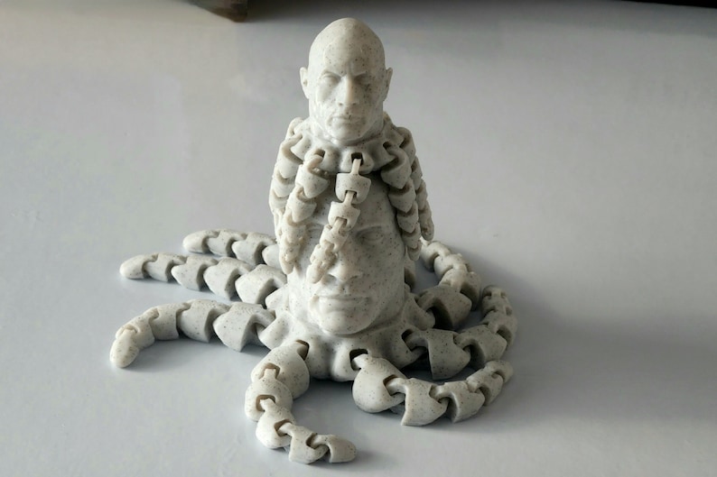 May include: A white 3D printed sculpture of a human head with multiple tentacles extending from the neck. The head has a serious expression and the tentacles are made of interlocking segments.
