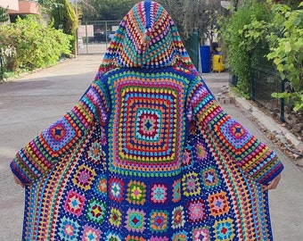 May include: A colorful crocheted cardigan with a hood, featuring a large square pattern of various colors. The cardigan is made with a blue background and has a multi-colored border.