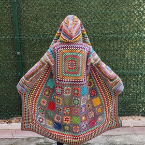 Könnte beinhalten: Ein farbenfroher Häkelcardigan mit Kapuze, der auf der Rückseite ein großes Granny-Square-Muster aufweist. Der Cardigan ist aus einer Vielzahl von leuchtenden Farben gefertigt, darunter Rot, Orange, Gelb, Grün, Blau und Lila.