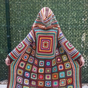 May include: A brown crochet cardigan with a hood, featuring a colorful granny square pattern. The cardigan is made with a variety of colors, including red, orange, yellow, green, blue, purple, and pink.