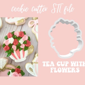 Op de afbeelding: Een witte koekjesvormer in de vorm van een theekopje met bloemen. De vormer wordt getoond op een roze achtergrond met de tekst "TEA CUP WITH FLOWERS" eronder.