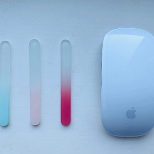 Peut inclure: Trois limes &agrave; ongles en verre avec des d&eacute;grad&eacute;s de couleurs : bleu &agrave; transparent, rose &agrave; transparent et rouge &agrave; transparent. Une souris Apple blanche avec le logo Apple est &eacute;galement dans l'image.