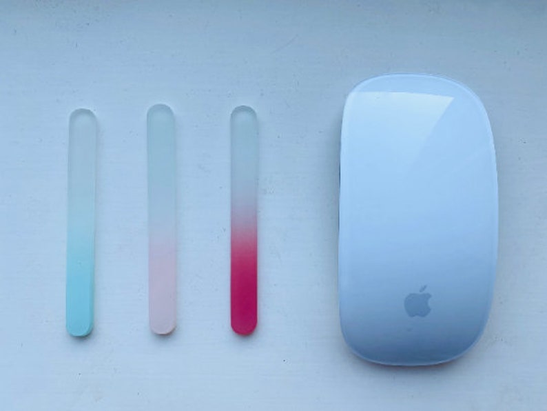Peut inclure: Trois limes &agrave; ongles en verre avec des d&eacute;grad&eacute;s de couleurs : bleu &agrave; transparent, rose &agrave; transparent et rouge &agrave; transparent. Une souris Apple blanche avec le logo Apple est &eacute;galement dans l'image.