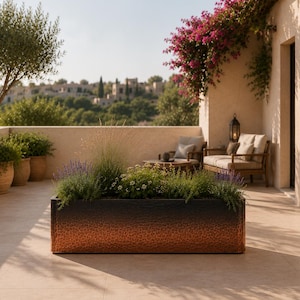 May include: A rectangular planter with a hammered metal texture, featuring a gradient finish that transitions from a dark charcoal black at the top to a warm, metallic copper at the base, filled with various green grasses and small white flowers.