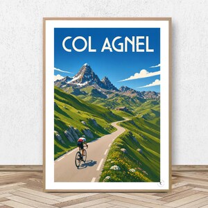 May include: A framed vertical poster featuring a cyclist riding on a winding mountain road. The text COL AGNEL is printed in white at the top. The scene depicts green grassy slopes, rocky mountain peaks under a blue sky, and small white flowers.