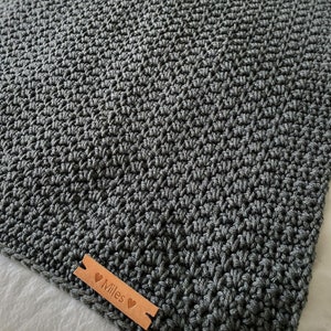 以下が含まれることがあります： グレーのクロシェ編みベビーブランケット。ブラウンの革タグには「Miles」と両側にハートマークが書かれています。