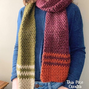 May include: A long, crocheted scarf with a green, white, and beige section on one side and a burgundy, orange, and red section on the other side.