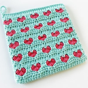 May include: A teal crochet pot holder with a repeating pattern of pink hearts.