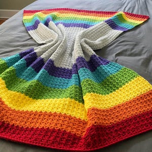 Może przedstawiać: Ręcznie robiony koc w kolorze tęczy z szarym środkiem i paskami w kolorze czerwonym, pomarańczowym, żółtym, zielonym, niebieskim i fioletowym.