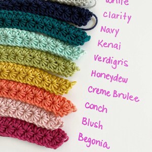 May include: A collection of crochet yarn samples in various colors, including white, navy, teal, green, yellow, orange, pink, and red. The colors are labeled with names like "Clarity", "Kena" and "Begonia".