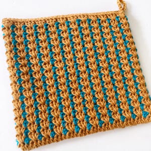 Puede incluir: Un agarrador de olla tejido a crochet con un patrón diagonal en amarillo mostaza y turquesa.