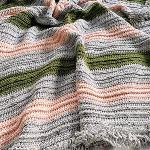 May include: A crocheted throw blanket with stripes of gray, pink, and green. The blanket has a fringe border.