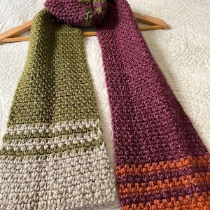 May include: A crocheted scarf with two different color patterns. One side is green and white, the other side is burgundy and orange.