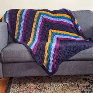 May include: A crocheted throw blanket with a navy blue background and stripes of purple, teal, and yellow.