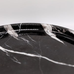 May include: A black and white marble serving tray with a raised rim. The tray has a smooth, polished surface.
