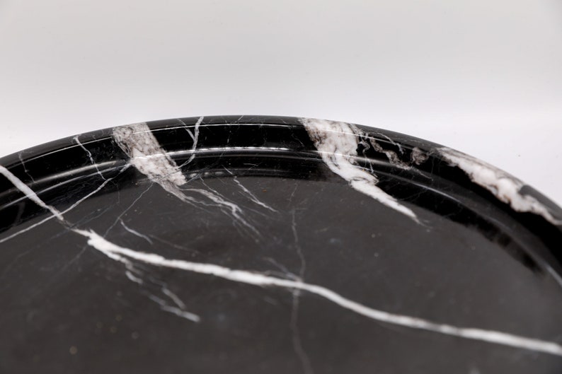 May include: A black and white marble serving tray with a raised rim. The tray has a smooth, polished surface.