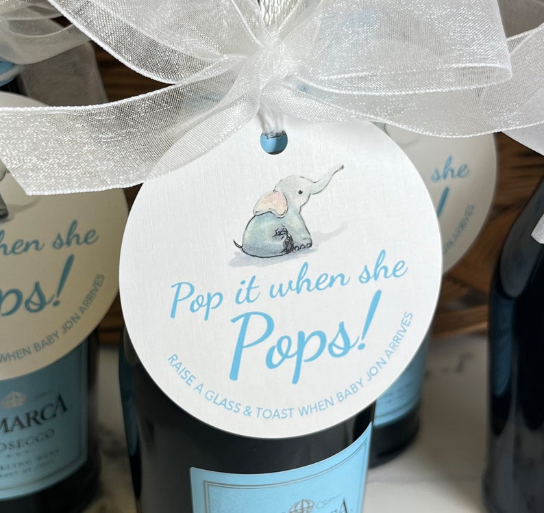 May include: A white round tag with a blue elephant illustration and the text 'Pop it when she Pops!' in blue. The tag is tied to a bottle of sparkling wine with a white ribbon. The text 'Raise a glass & toast when baby Jon arrives' is also on the tag.
Pop It When She Pops Personalized Baby Shower Mini Champagne Bottle Favor Tag Prosecco Elephant Gift Tag Custom Baby Shower Gift Tag