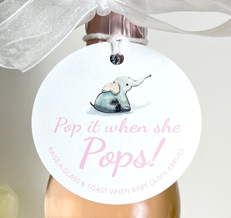 May include: A white round tag with a pink elephant illustration. The tag has the text 'Pop it when she Pops!' in pink lettering. Below the text, it reads 'Raise a glass & toast when baby Olivia arrives'.
Pop It When She Pops Personalized Baby Shower Mini Champagne Bottle Favor Tag Prosecco Elephant Gift Tag Custom Baby Shower Gift Tag